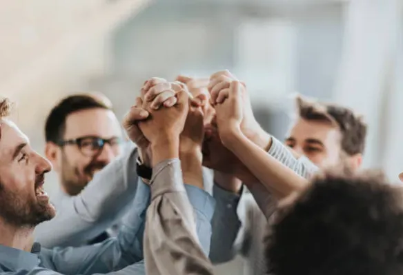 Collaborateurs se tenant les mains en l'air illustrant un engagement collectif